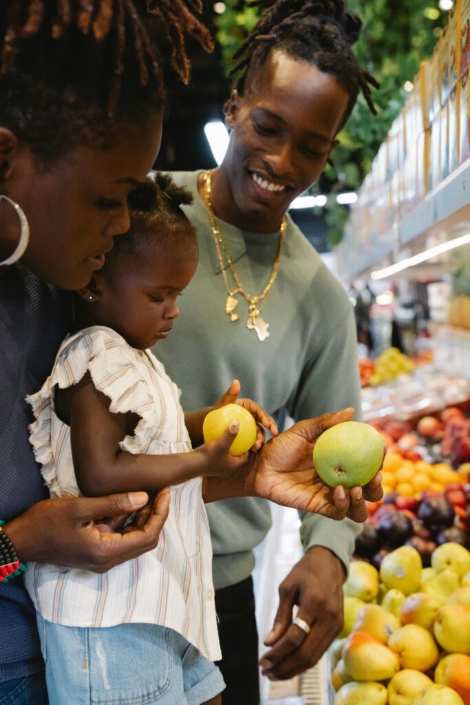 Family shopping together, exploring fresh fruits in a brightly lit supermarket.